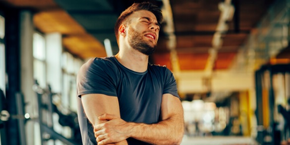 man holding his elbow and tricep with pain expression stock image