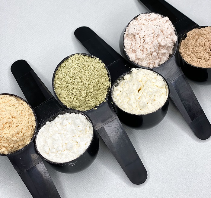various protein powders in scoops side by side