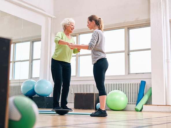 trainer helping an older woman at exercise studio stock image