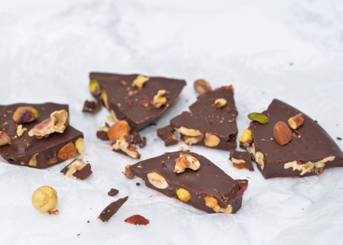 chocolate bark with nuts broken pieces on background
