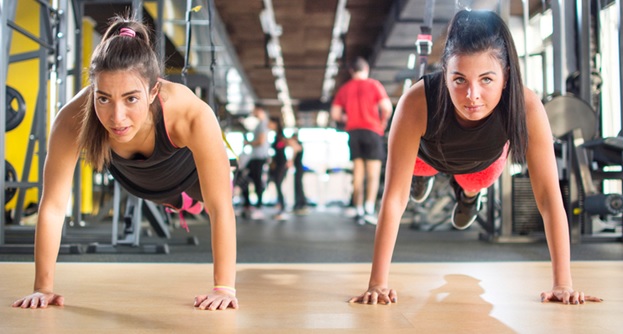 two women doing pushups together at gym stock image