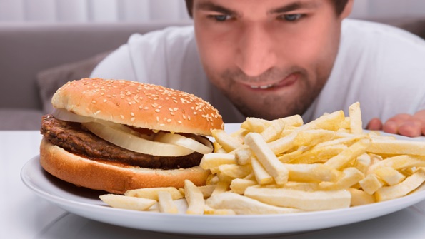 man looking at a burger and fries licking lips stock image