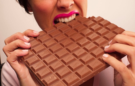 woman taking a bite out of a large block of chocolate stock image