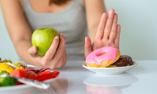 woman with an apple showing no to donuts stock image
