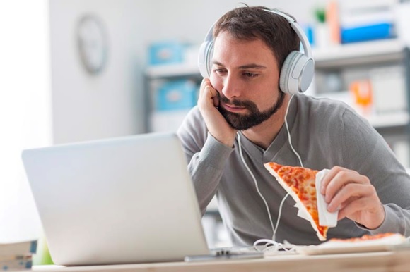 man eating pizza and watching laptop stock image