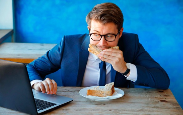 man eating and working on laptop stock image