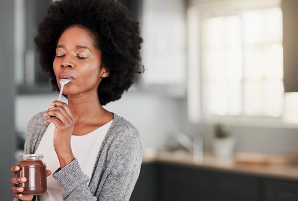 woman eating chocolate spread from the jar with a spoon stock image