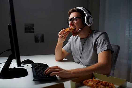 man at computer desk eating with one hand stock image