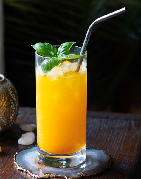glass with ice and orange liquid straw stock image