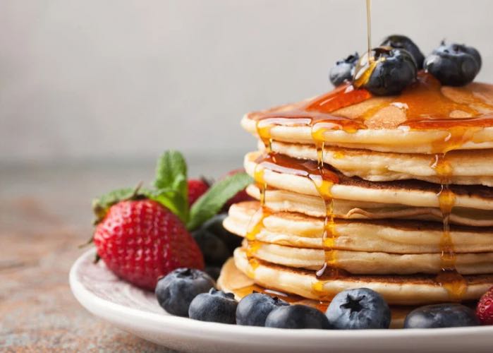 stack of pancakes on a plate with fruit side profile 