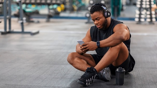 man sitting on the gym floor on phone stock image