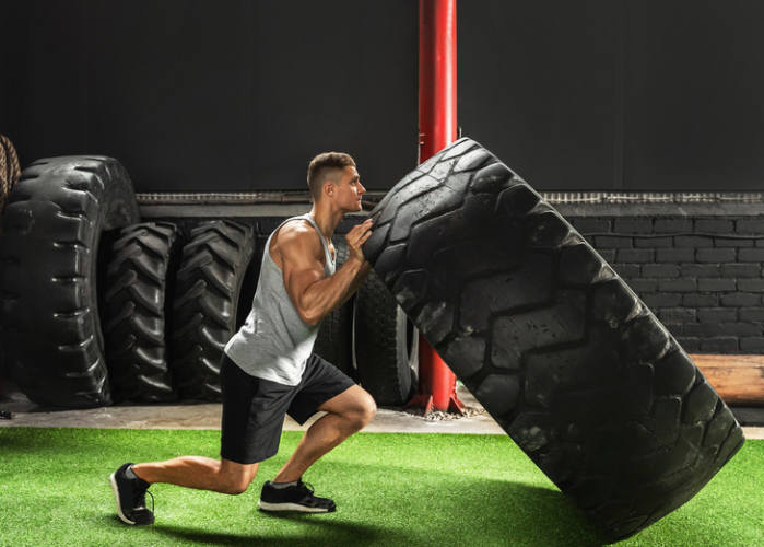 man flipping large tyre in gym