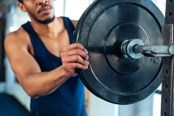 man putting plate on a barbell stock image