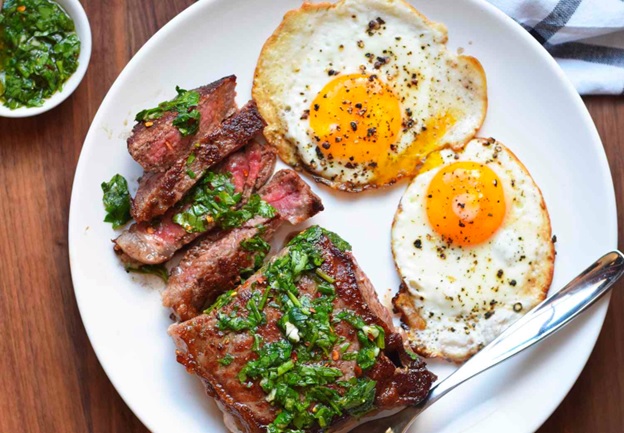 meat and eggs on a white plate stock image