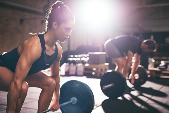 woman and man lifting barbells in gym stock image