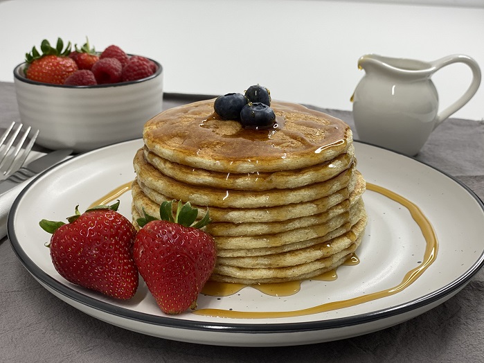 protein pancake stack on a plate with fruit and low cal syrup
