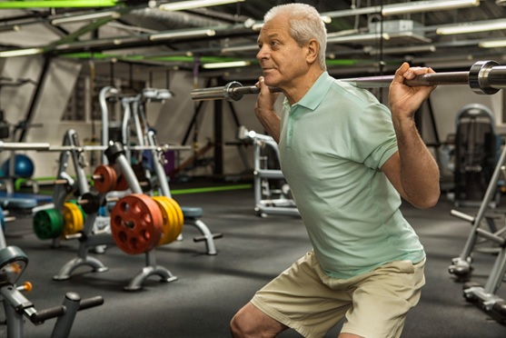 older man squatting a barbell at the gym stock image