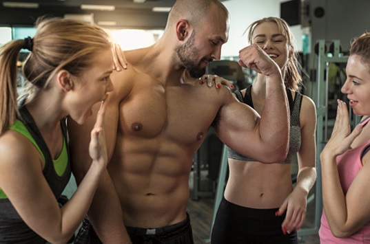 fit man surrounded by females at the gym stock image