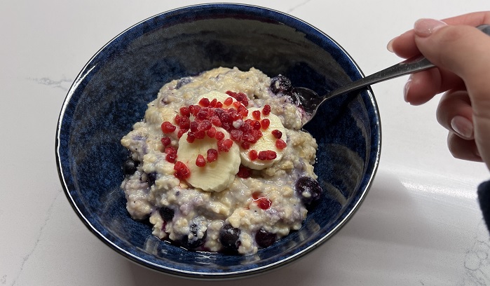 protein oats cooked in blue bowl with berries and spoon