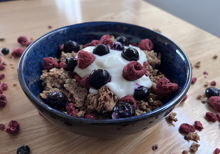 protein granola in blue bowl with yoghurt and berries side on