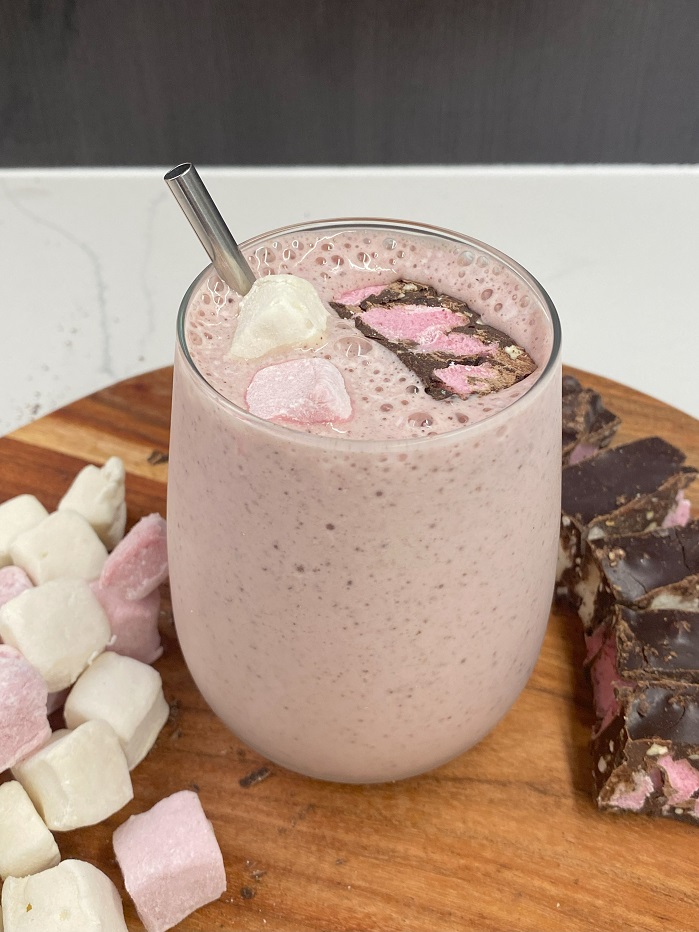 protein rocky road smoothie served in a glass with metal straw
