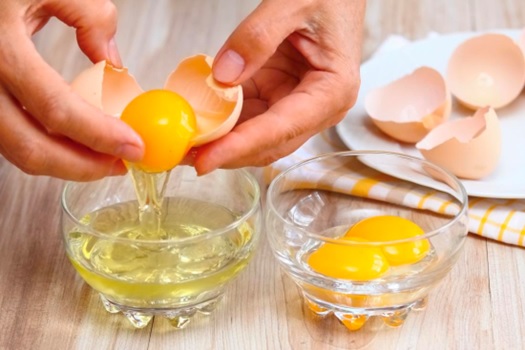 separating eggs from whites in two cups stock image