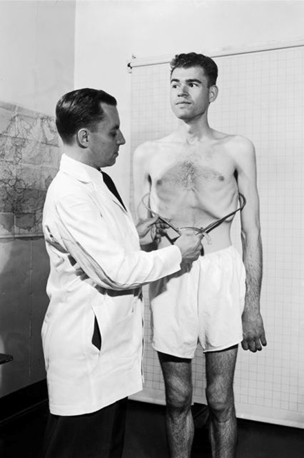 doctor examining thin patient's waistline black and white