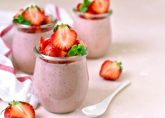 strawberry protein mousse with cut strawberries on top in glass jars