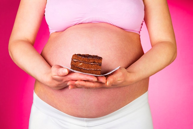 pregnant woman holding a slice of cake stock image