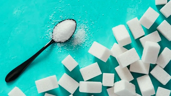 cubes of sugar on a blue table with teaspoon stock image