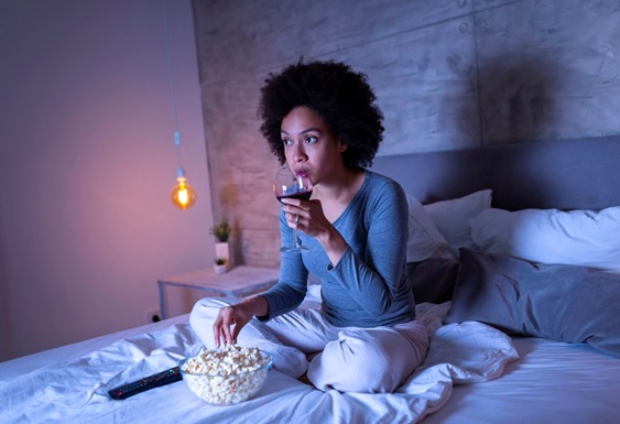 woman up at night drinking and eating snacks watching tv stock image