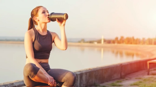 active woman drinking from a protein shaker at the beach stock image