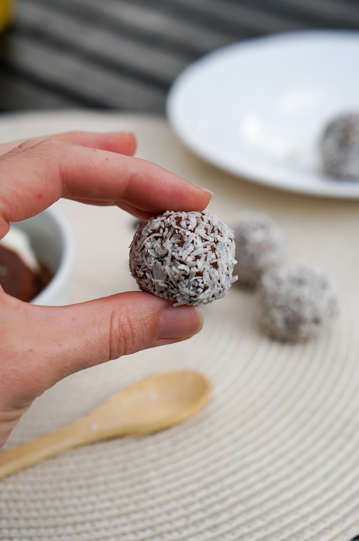 holding a weetbix protein ball with shredded coconut