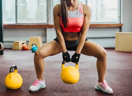 woman doing kettlebell sumo squats 