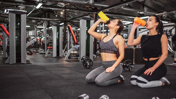 women drinking from protein shakers in the gym