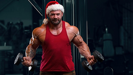 muscly man with xmas hat and red singlet lifting dumbells stock image